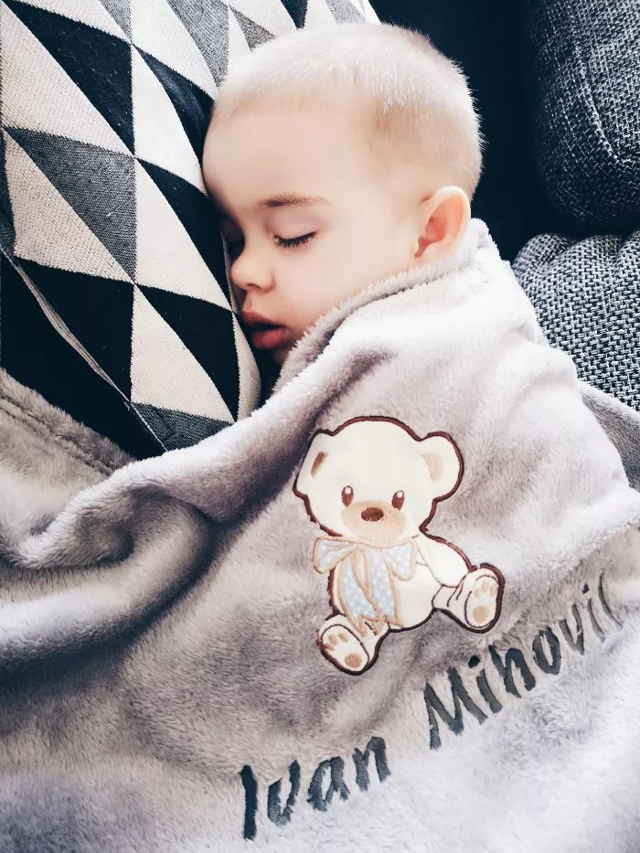 Mali dječak spava pokriven svojom personaliziranom sivom dekicom