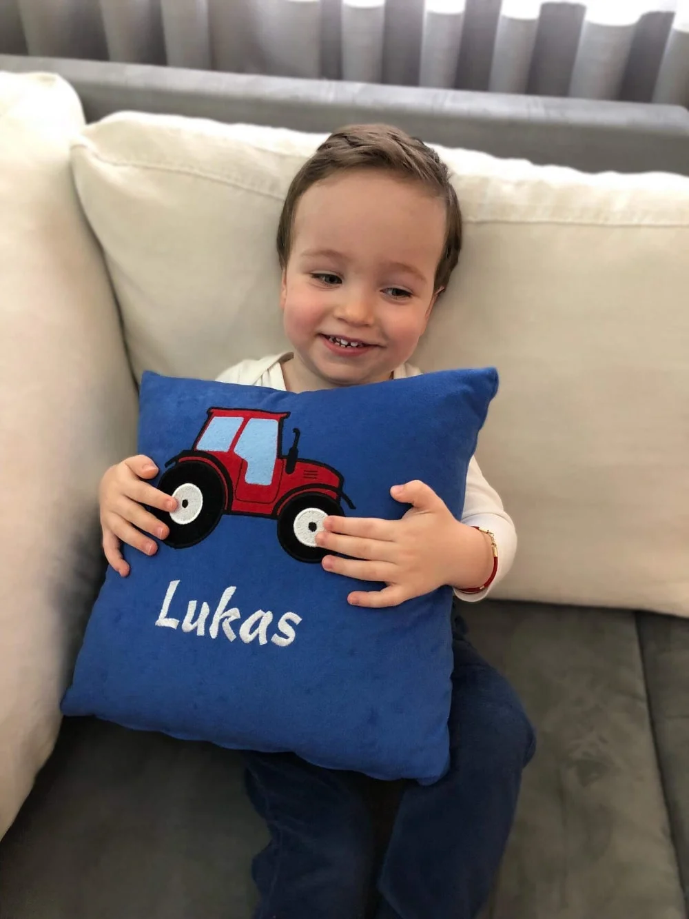 Dječak s ponosom pokazuje svoj personalizirani jastučić, s živopisnim dizajnom i svojim imenom.