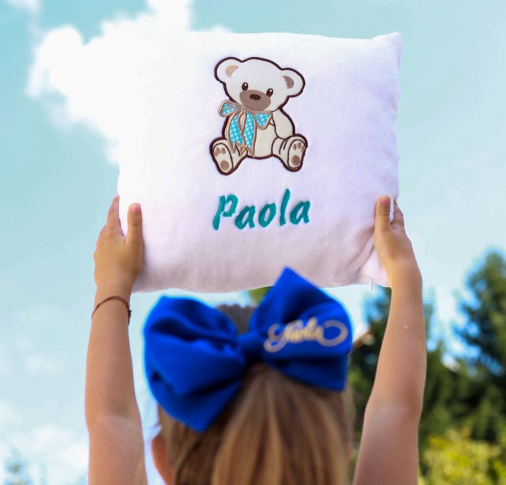 Djevojčica s ponosom pokazuje svoj personalizirani jastučić, s živopisnim dizajnom i svojim imenom.